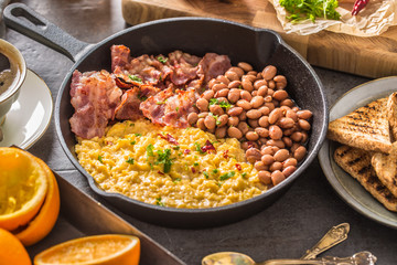 Full table of english breakfast. Scrambled eggs grilled bacon beans toast bread orange juice and coffee