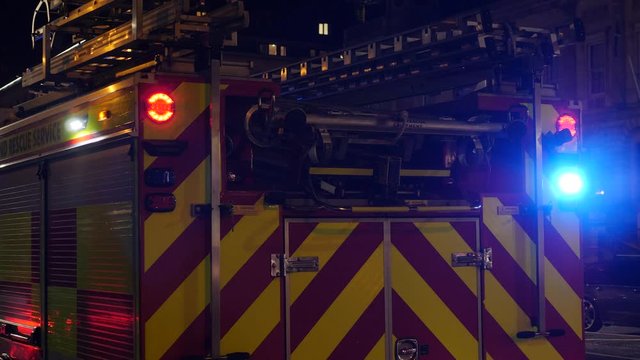 4K: UK Fire Engine at Night with lights flashing and sirens going. Fire Department Truck