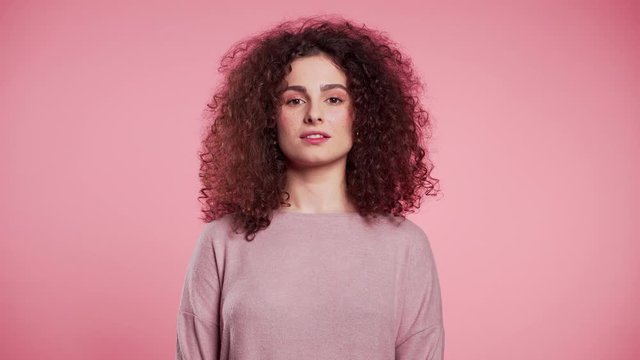 Young curly woman with trendy glitter freckles make-up. Portrait of flirting beautiful girl on pink studio background.