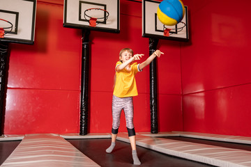 Happy child girl playing basketball and having fun in jump park