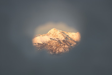 Snowy mountain at sunset seen through a hole