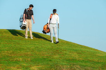 Stylish friends spending time together while playing golf on golf course