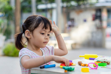 Hearing impaired children playing clay mold on the table in the park.