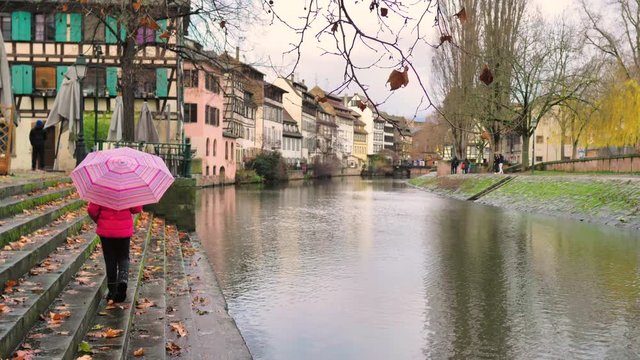 Ni&ntilde;a con paraguas rosa camina en escalinata de canal de Estrasburgo