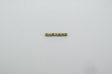 TUESDAY spelled out in gold dice blocks on white background.