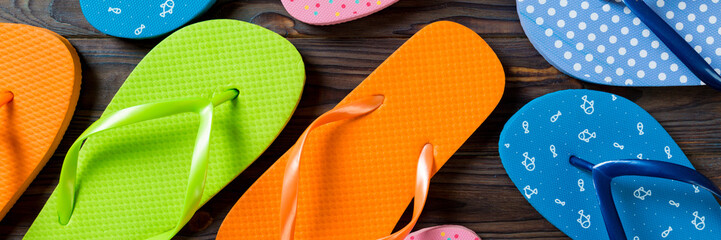 a lot of flip flop colored sandals, summer vacation on wooden background, banner copy space top view