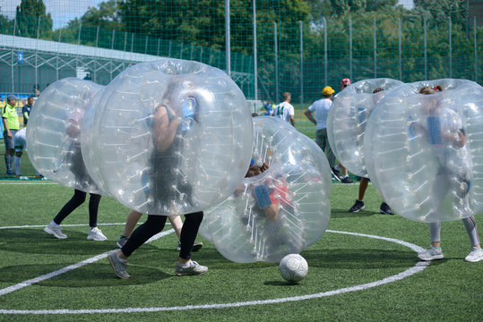 Bubble football. People kicking ball on a football field