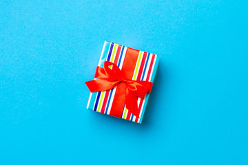 Gift box with red bow for Christmas or New Year day on blue background, top view with copy space