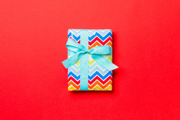 wrapped Christmas or other holiday handmade present in paper with blue ribbon on red background....
