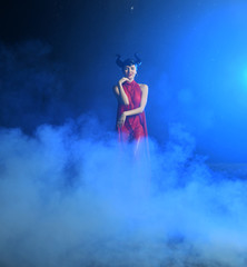 beautiful girl in clothes of the goddess of the earth in the rain in smoke on a black background