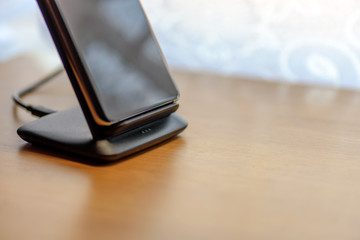 smartphone wireless charging on charging stand on wooden table