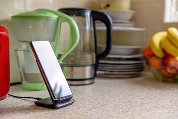 smartphone wireless charging on charging stand on kitchen tabletop