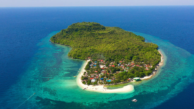 Himokilan Island, Leyte Island, Philippines. Tropical island with a village and a white beach. Turquoise water and coral reefs around the island. Summer holiday vacation concept.