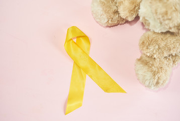 Childhood Cancer Awareness Golden Ribbon and stethoscope on yellow background. Childhood Cancer Day February, 15.  W