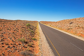 Paved road running through red dunes