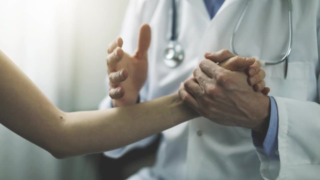 doctor talking about diagnosis while holding patient hand in clinic office