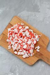 Crab stick sliced on a cutting Board, on a gray background.  Delicious crab sticks cooked for food. concept of cooking food, dish, salad. Seafood for salad. the view from the top.