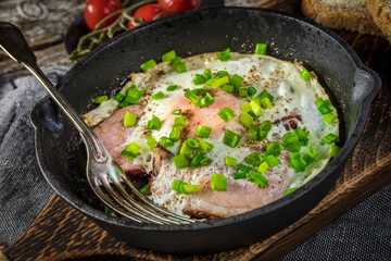 Fried eggs with ham on an old wooden background.