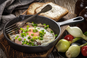 Fried eggs with ham on an old wooden background.