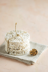Stack of rice cakes. American puffed rice cakes. Healthy snacks with walnut on light pink concrete surface. Close up..