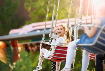 Little girl having fun on chain carousel. Happy summer memories. Carefree childhood and happiness