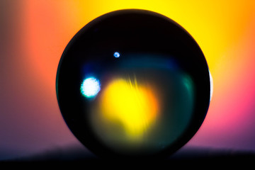 A glass ball illuminated from behind with colored lights. Macrophotography of the ball with illumination and reflection