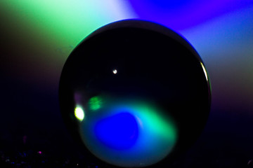 A glass ball illuminated from behind with colored lights. Macrophotography of the ball with...