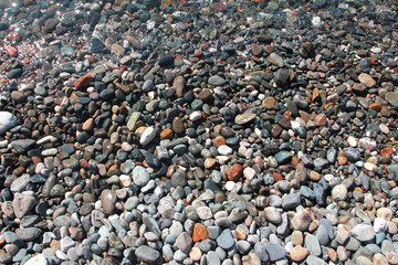 Little pebbles under the water surface photo background summer sea