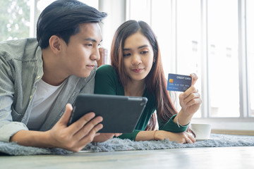 Obraz premium Couples help each other online shopping with credit cards.