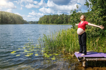 Fototapeta na wymiar Pregnant woman enjoying nature in a summer forest