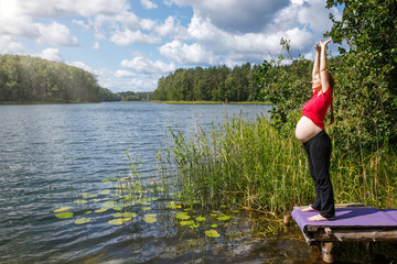 Fototapeta na wymiar Pregnant woman stretching in a summer forest
