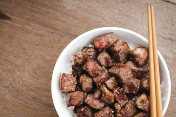 Homemade Bowl of Diced Beef Steak with rice Japanese style on wooden table.