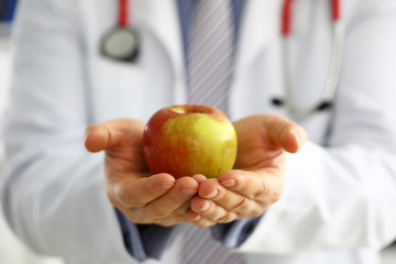 Male medicine therapeutist doctor hands holding red fresh ripe apple