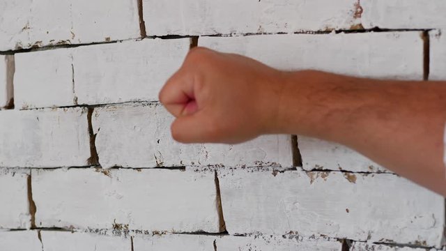 male hand knocking on a brick wall