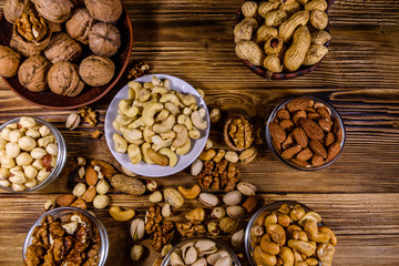 Various nuts (almond, cashew, hazelnut, pistachio, walnut) in bowls on a wooden table. Vegetarian meal. Healthy eating concept. Top view