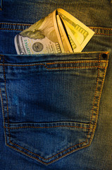 American banknotes in jeans pocket. A note in denominations of $ 100 peeps, stick out from the back, the foremost pants pocket. Money falls out of pocket. Flare effect. View from different angles