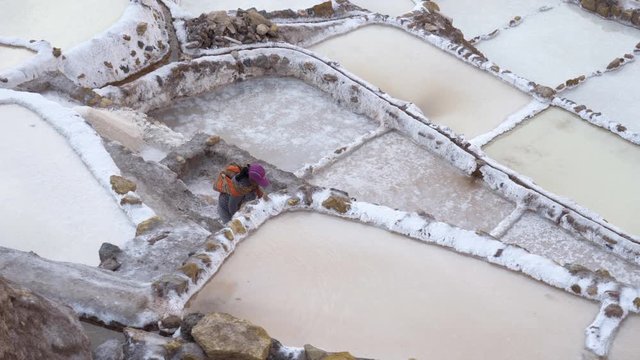 Salinas de Maras in the Sacred Valley of the Incas near Cusco, Peru in the Andes Mountains - Old woman walking between salt ponds