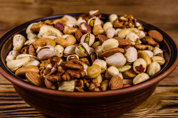 Various nuts (almond, cashew, hazelnut, pistachio, walnut) in ceramic plate on a wooden table. Vegetarian meal. Healthy eating concept