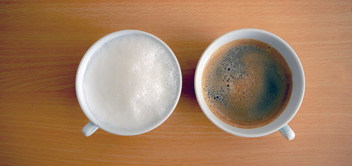 a cup of hot milk and a cup of espresso on wooden table