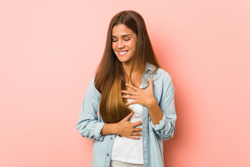 Young slim woman laughs happily and has fun keeping hands on stomach.