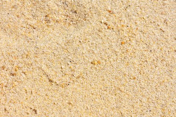 Golden wet sand background with selective focus. Textured yellow sand surface with soft focus. Summertime. Beach vacation. Seascape with clean sand.