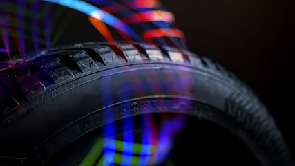 Fototapeta na wymiar automobile tire in colorful neon rays on a dark background