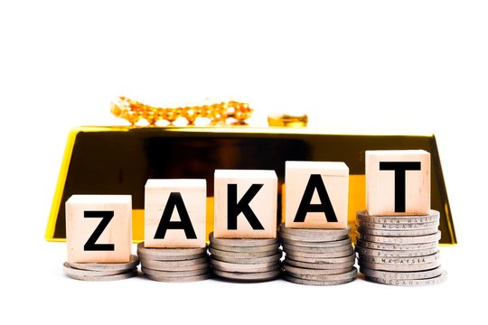Concept of zakat in Islam religion. Selective focus of money and rice with  alphabet of zakat on wooden background.