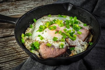 Fried eggs with ham on an old wooden background.