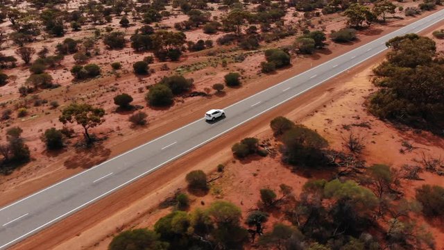 Aerial view of white suv car traveling a beautiful Australian Outback Road