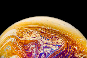 Rainbow soap bubble on an isolated black background. Close-up of the colorful surface. Poster blank