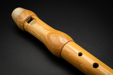 Fototapeta premium A wooden soprano recorder lying on black background