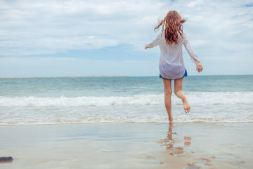 Naklejka premium Young woman running playful on tropical beach in freedom.