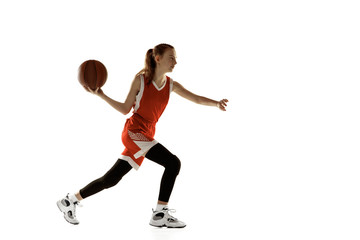 Young caucasian female basketball player in action, motion in run isolated on white background. Redhair sportive girl. Concept of sport, movement, energy and dynamic, healthy lifestyle. Training.