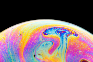 Fototapeta na wymiar Rainbow soap bubble on an isolated black background. Close-up of the colorful surface. Poster blank